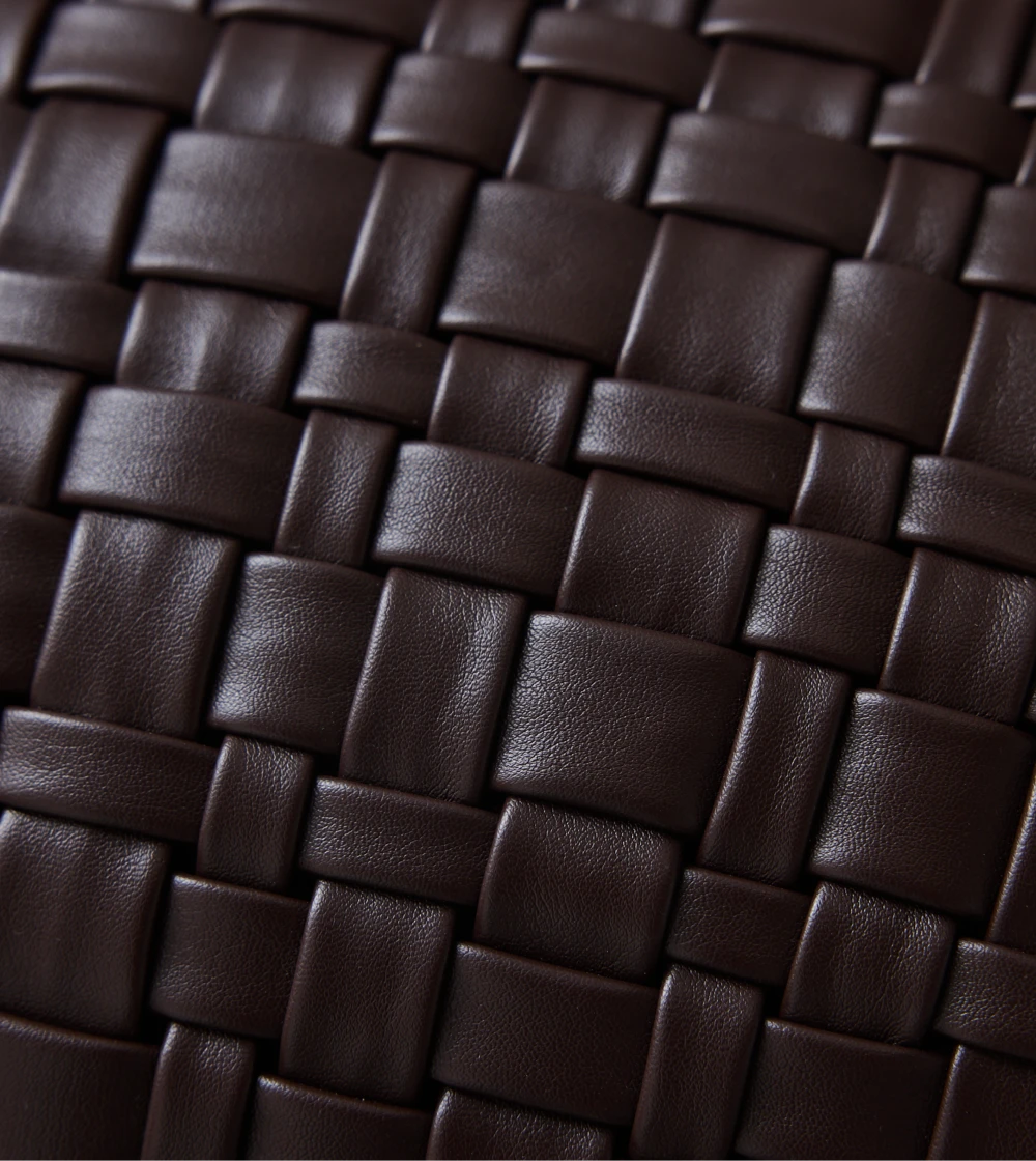Cojín color marrón chocolate con superficie tejida de HKLIVING sobre sofá, aportando textura y estilo decorativo