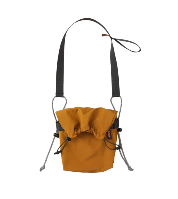 Bolso bandolera pequeño Small Drawstring Sling A110 de PACKBAGS en color mostaza, con cierre de cordón y correa ajustable con detalle reflectante.