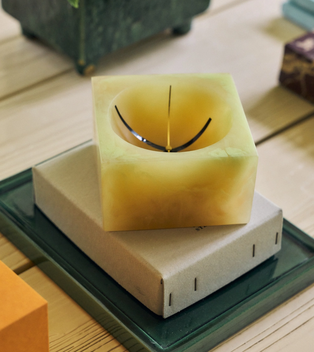 Resin Table Clock Soft Yellow de HKLIVING, reloj de sobremesa de resina amarilla con acabado marmoleado y esfera redonda integrada en una estructura cuadrada.