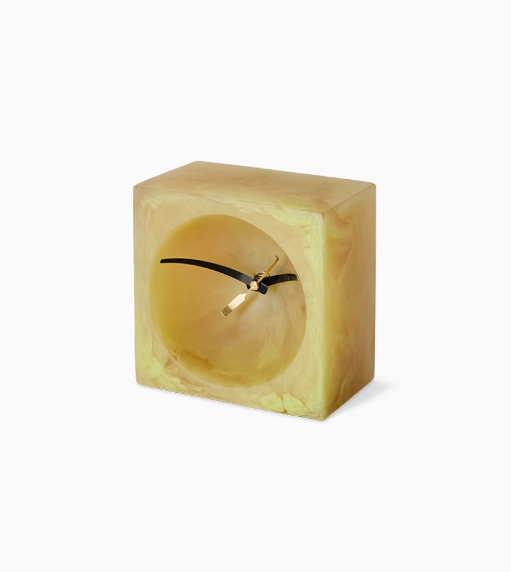 Resin Table Clock Soft Yellow de HKLIVING, reloj de sobremesa de resina amarilla con acabado marmoleado y esfera redonda integrada en una estructura cuadrada.
